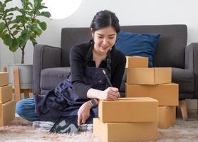 Retrato de mujer joven asiática SM trabajando con una caja en casa el lugar de trabajo.Propietario de una pequeña empresa de inicio, pequeña empresa emprendedora o empresa independiente en línea y concepto de entrega. foto