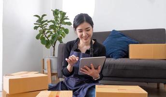 Starting small businesses SME owners female entrepreneurs Use a laptop or notebook to receive and review orders online to prepare to pack boxes, sell to customers, SME online business ideas. photo
