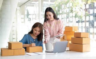 Portrait of Starting small businesses SME owners, two Asian woman check online orders Selling products working with boxs freelance work at home office, sme business online small medium enterprise photo