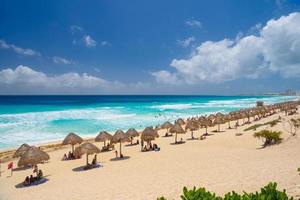 sombrillas en una playa de arena con agua azul en un día soleado cerca de Cancún, México foto