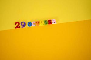 October 29 on a yellow, paper background with wooden and multicolored letters with space for text. photo