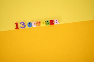 October 13 on a yellow, paper background with wooden and multicolored letters. photo