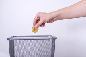 hand gettting out bitcoin in trash container. photo