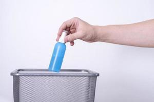 A hand throws perfume into a trash can. photo