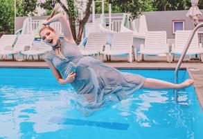 bella mujer con vestido gris saltando en la piscina foto