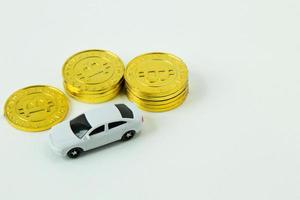 juguete de coche blanco y moneda de oro sobre fondo blanco. foto