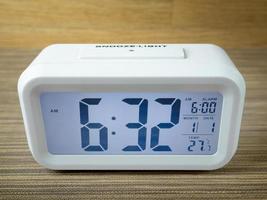 The white alarm clock digital numbers on wood table. photo
