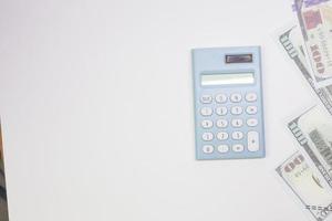 calculadora azul y billetes en fondo blanco. foto