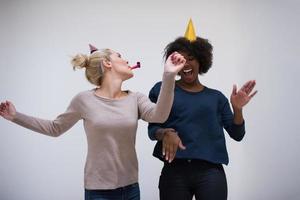 mujeres sonrientes con gorras de fiesta que soplan silbatos foto