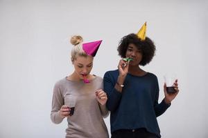 smiling women in party caps blowing to whistles photo