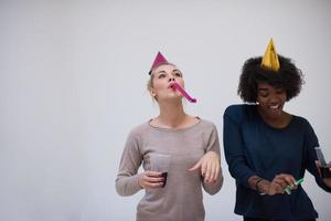 mujeres sonrientes con gorras de fiesta que soplan silbatos foto