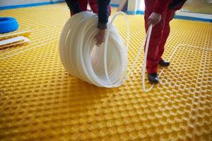 workers installing underfloor heating system photo