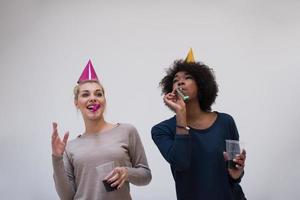 mujeres sonrientes con gorras de fiesta que soplan silbatos foto