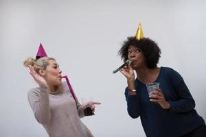 mujeres sonrientes con gorras de fiesta que soplan silbatos foto