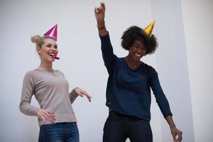 smiling women in party caps blowing to whistles photo