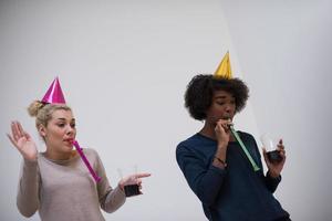 mujeres sonrientes con gorras de fiesta que soplan silbatos foto