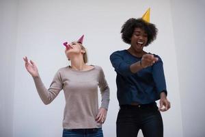 mujeres sonrientes con gorras de fiesta que soplan silbatos foto