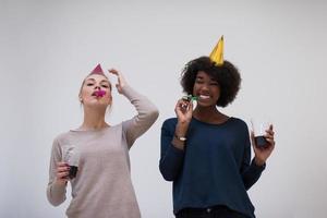 mujeres sonrientes con gorras de fiesta que soplan silbatos foto