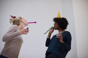 mujeres sonrientes con gorras de fiesta que soplan silbatos foto