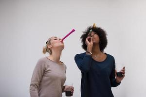 mujeres sonrientes con gorras de fiesta que soplan silbatos foto