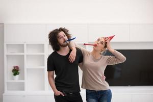 couple in party hats blowing in whistle photo