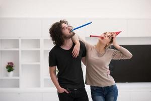 couple in party hats blowing in whistle photo