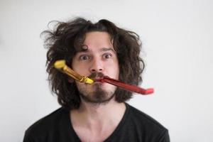 Portrait of a man in party hat blowing in whistle photo