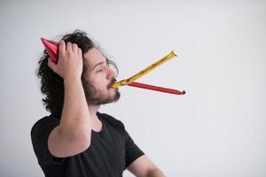 Portrait of a man in party hat blowing in whistle photo