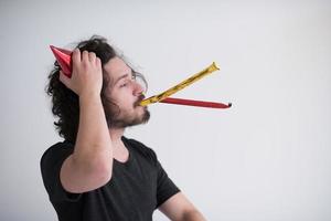 Portrait of a man in party hat blowing in whistle photo