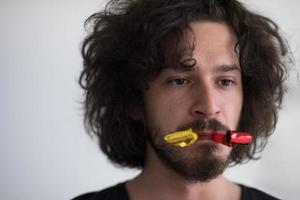 Portrait of a man in party hat blowing in whistle photo