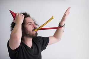 Portrait of a man in party hat blowing in whistle photo