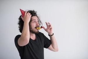 Portrait of a man in party hat blowing in whistle photo