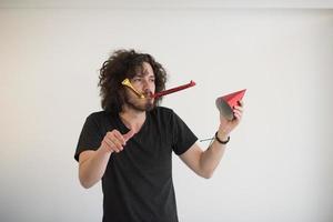 Portrait of a man in party hat blowing in whistle photo