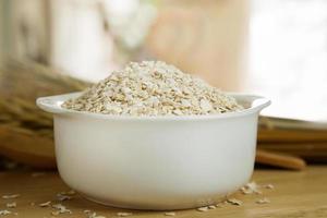 The Healthy breakfast cereal oat flakes in bowl on wooden table. photo