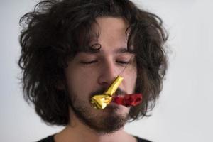 Portrait of a man in party hat blowing in whistle photo