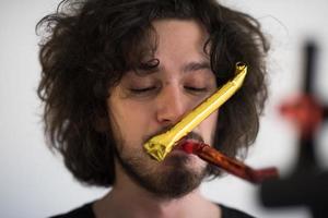 Portrait of a man in party hat blowing in whistle photo