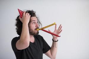 Portrait of a man in party hat blowing in whistle photo