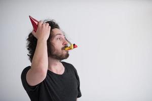 Portrait of a man in party hat blowing in whistle photo