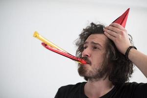 Portrait of a man in party hat blowing in whistle photo