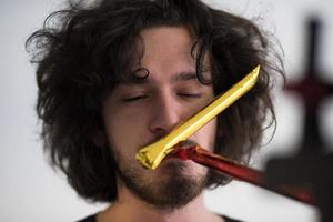 Portrait of a man in party hat blowing in whistle photo