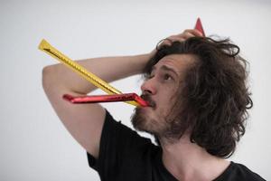 Portrait of a man in party hat blowing in whistle photo