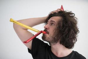 Portrait of a man in party hat blowing in whistle photo