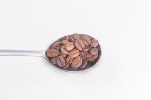 roasted coffee beans in stainless spoon on white background space modern style. photo