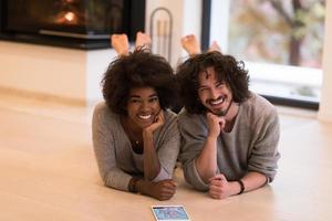 multiethnic couple lying on the floor  in front of fireplace photo