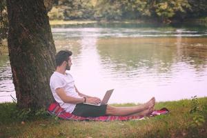 hombre usando una computadora portátil en la orilla del río foto