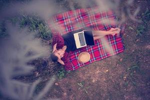 top view of man using a laptop computer under the tree photo