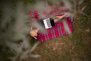 top view of man using a laptop computer under the tree photo
