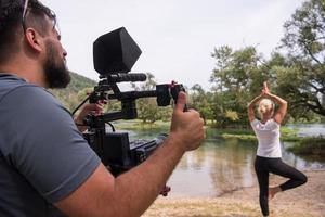 young videographer recording while woman doing yoga exercise photo