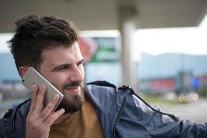 apuesto joven casual hombre de negocios con barba usando teléfono celular foto