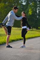 pareja haciendo ejercicio de estiramiento después de trotar foto